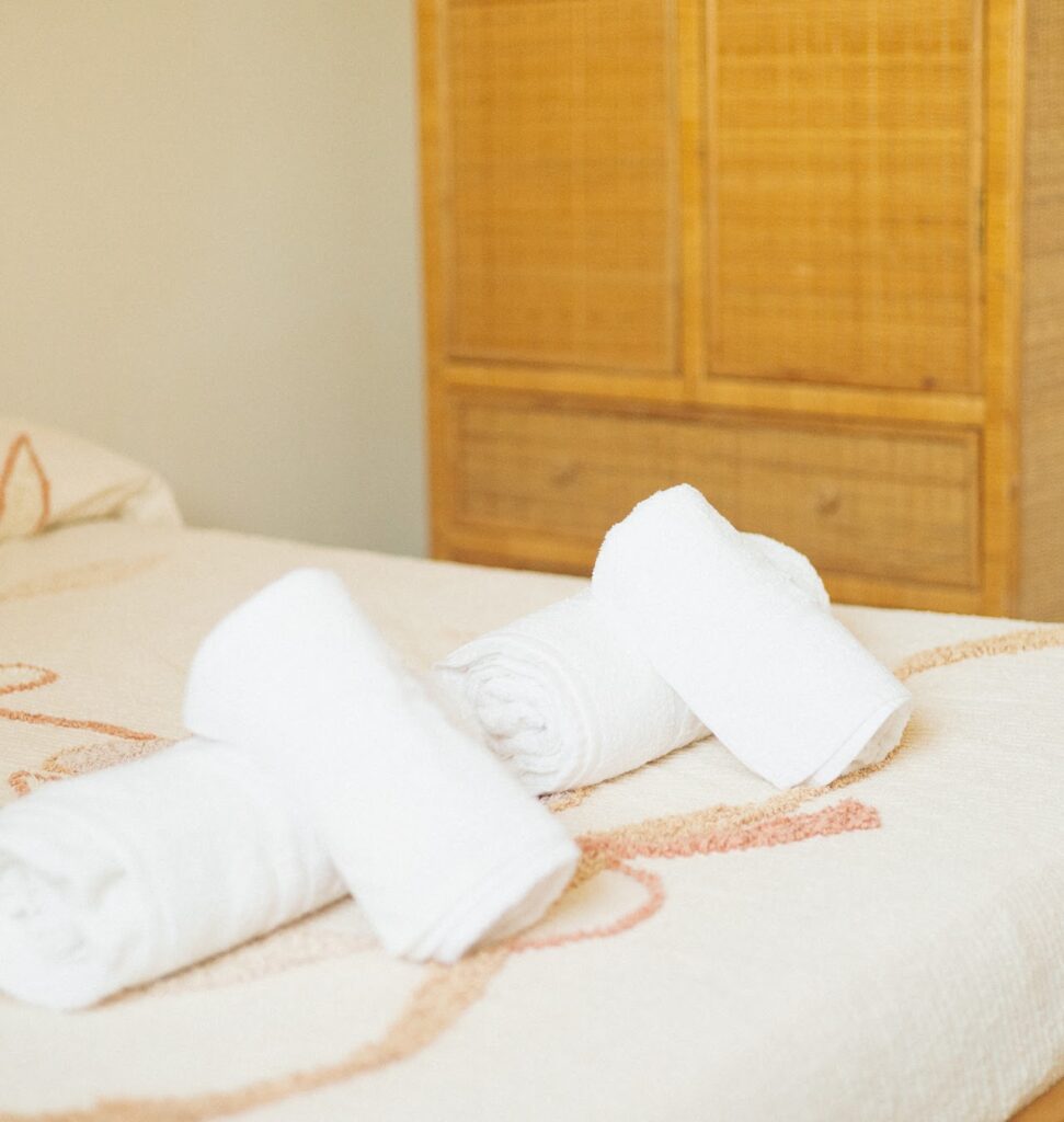 Ensuite room with a dedicated office space and fresh white towels at Masseria Olga coliving in Italy.