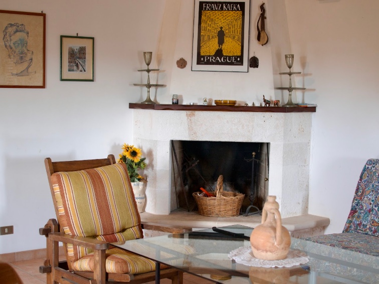 Cozy lounge area with fireplace and armchairs at a coliving in Italy