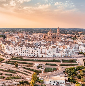 Whitewashed hilltop village of Locorotondo surrounded by countryside near Masseria Olga coliving in Italy.