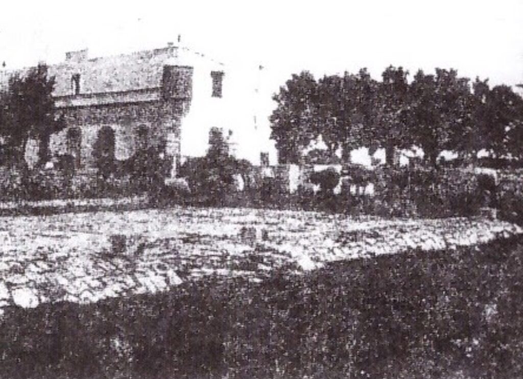 Black and white photo of Masseria Olga being built in 1917 in rural Puglia, Italy, surrounded by trees and traditional stone structures
