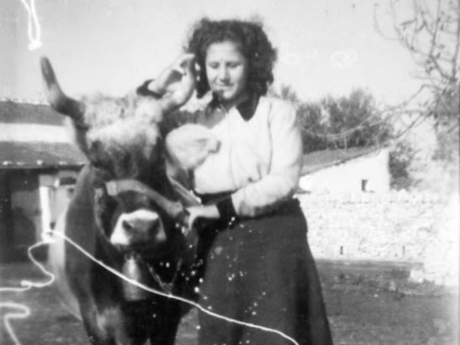 Sepia photo of young Olga smiling and petting a horse at Masseria Olga in rural Italy