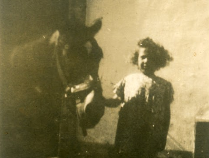 Black and white photo of Olga hugging a cow in front of the farmhouse at Masseria Olga, Puglia