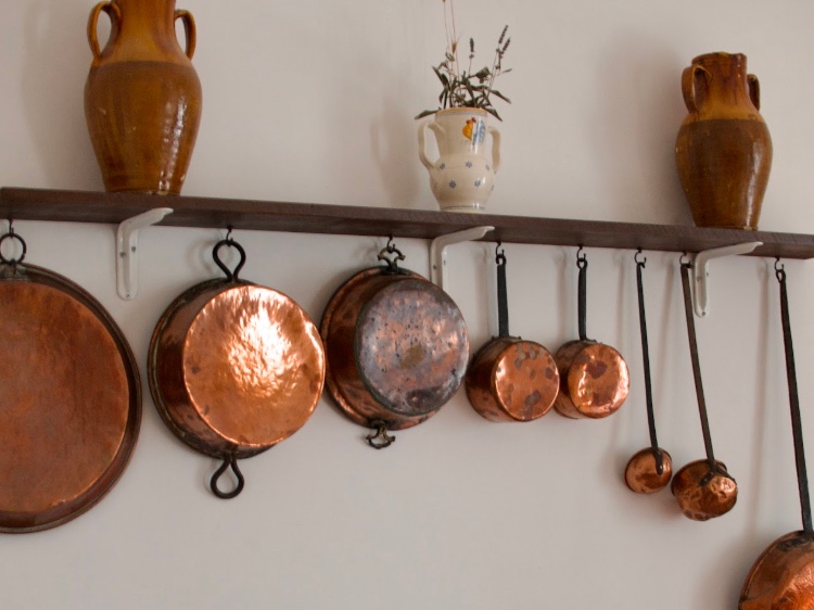 Copper pans hanging on the wall in a shared kitchen at a coliving in Italy