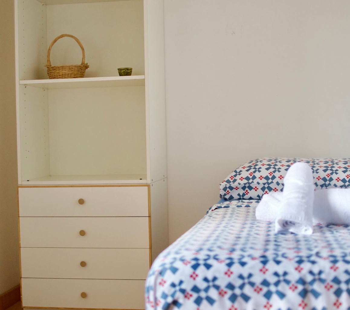 Cozy single room with a patterned bedspread and a built-in storage unit at Masseria Olga coliving in Italy.